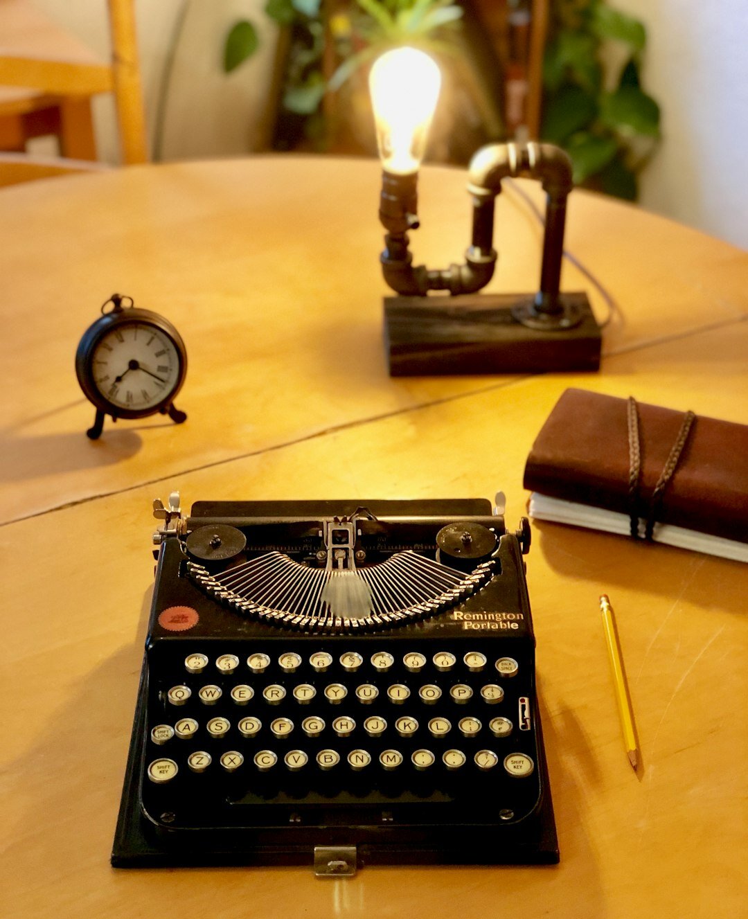 Vintage wooden writing desk with a typewriter, a cup of coffee and an open notebook under warm lamp light